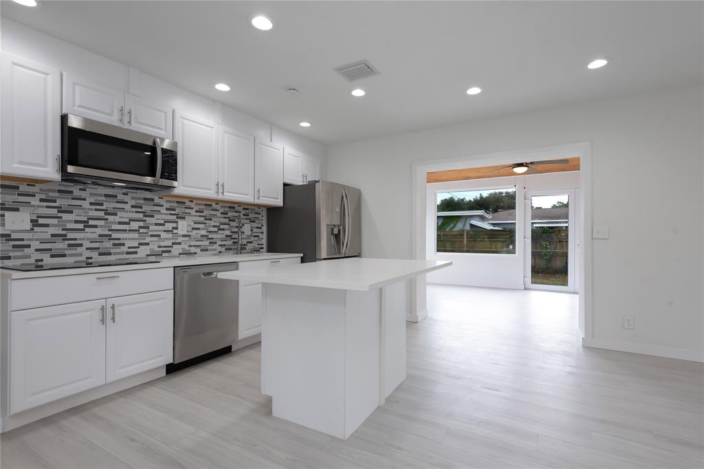 713 Southwest 4th Court Hallandale Beach, FL 33009 - Photo 31 of 38 a kitchen with stainless steel appliances kitchen island granite countertop a stove a sink and a microwave