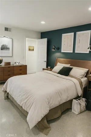 a bedroom with a bed and painting on the wall