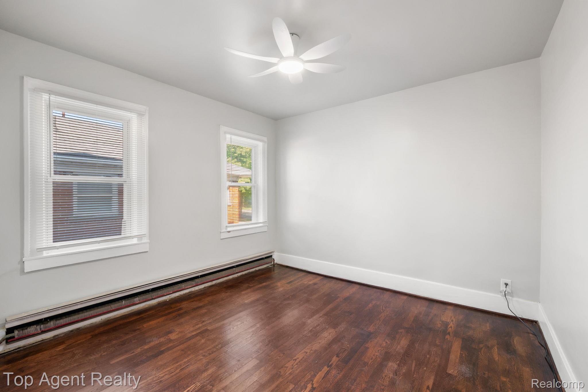 19217 Reno Street Detroit, MI 48205 - Photo 17 of 45 Hardwood flooring, two windows, baseboard heating, ceiling fan, and light-toned wall paint