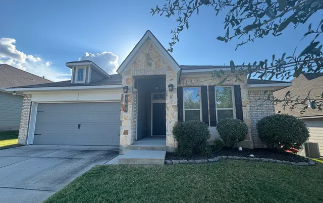 a view of a house with brick walls and a yard with plants