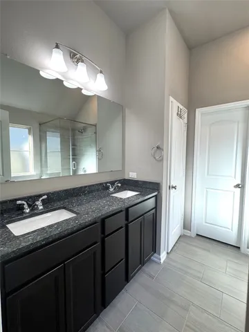 a bathroom with a granite countertop sink a large mirror and a shower