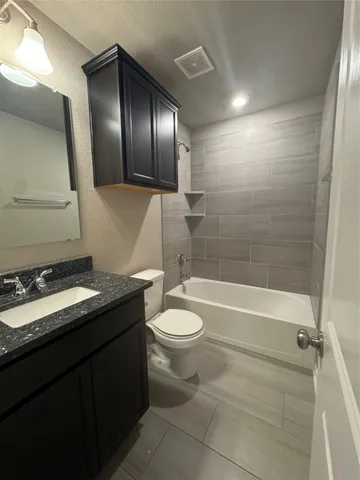 a bathroom with a granite countertop sink toilet mirror and bathtub