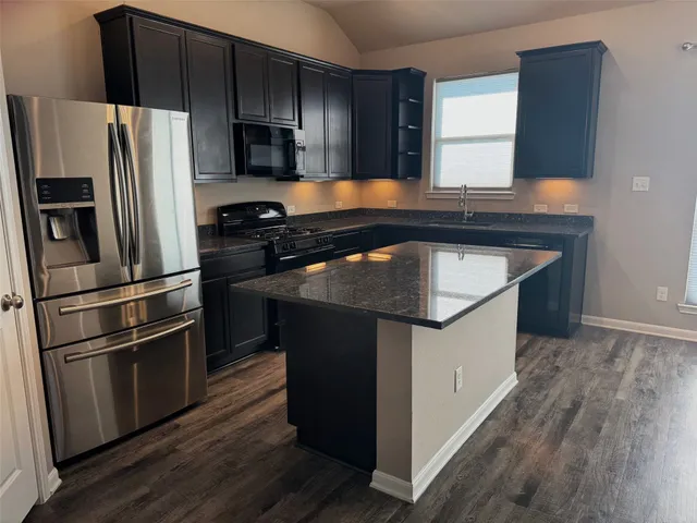 a kitchen with granite countertop a sink stove and refrigerator