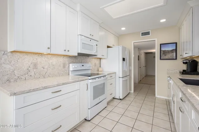 a kitchen with granite countertop white cabinets and white appliances