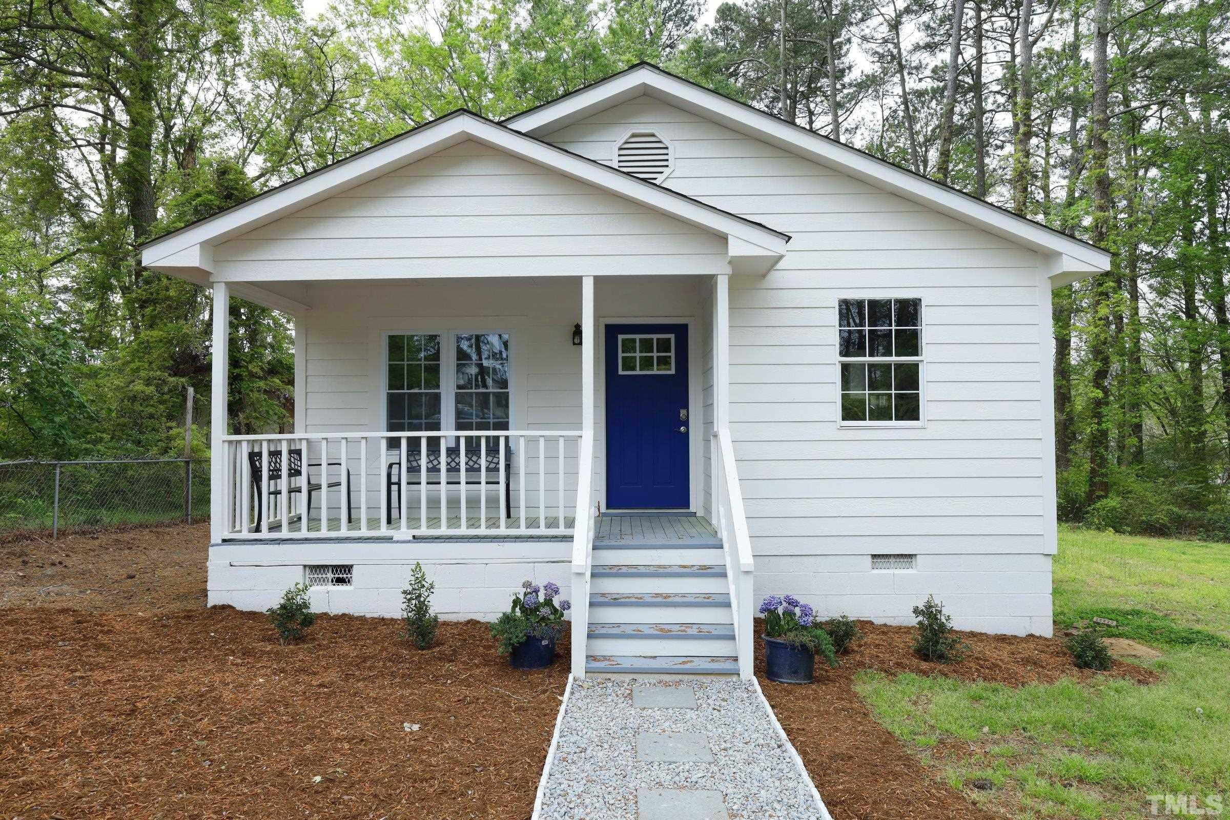 a view of small white house with large windows and a small yard