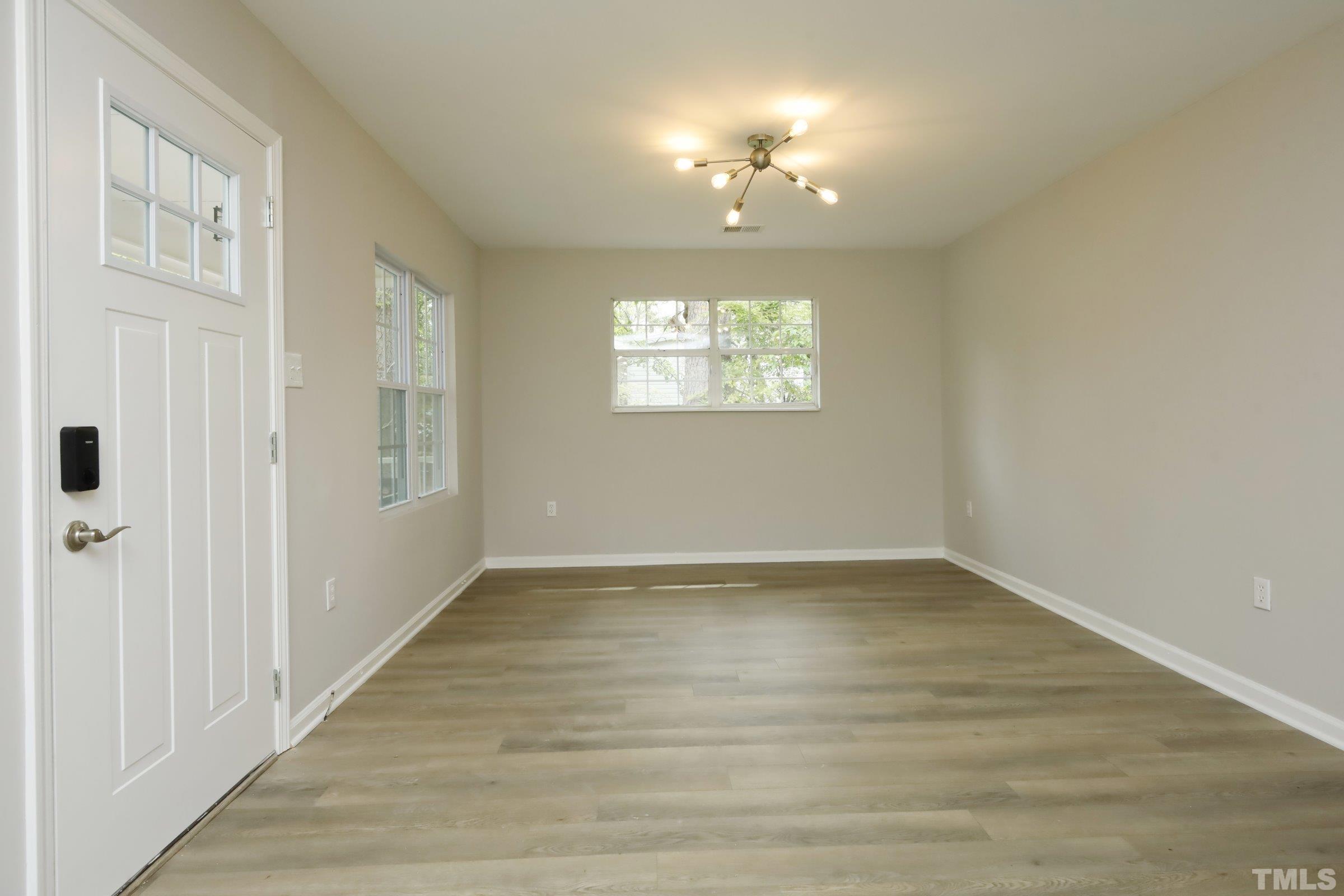 100 Mitchener Street Garner, NC 27529 - Photo 28 of 37 an empty room with wooden floor chandelier and windows