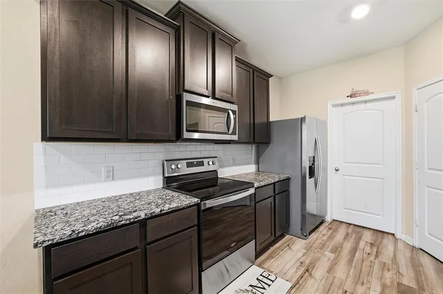 a kitchen with stainless steel appliances granite countertop a refrigerator and a stove top oven