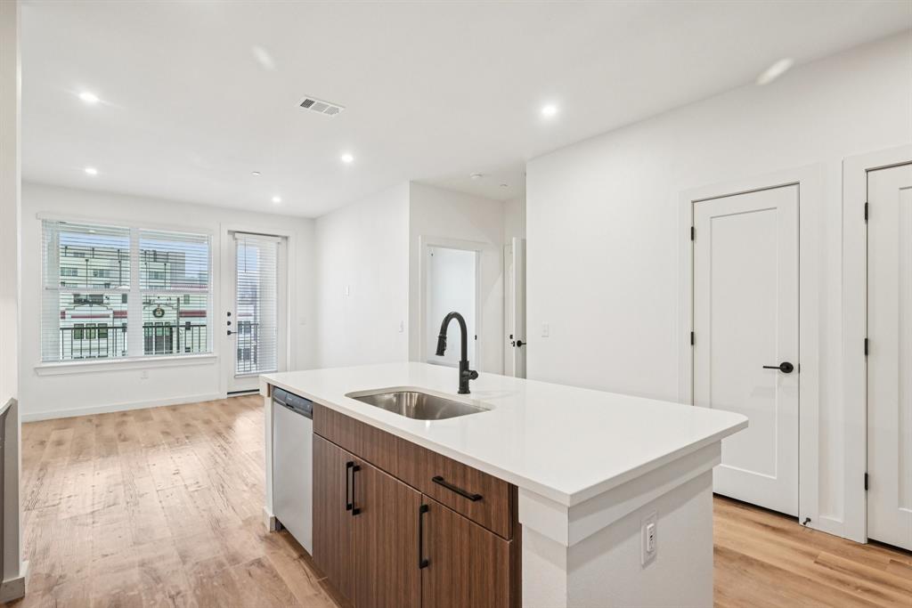 2016 South Ervay Street, Unit A1 Dallas, TX 75215 - Photo 10 of 35 Kitchen with light wood-style flooring, an island with sink, brown cabinets, recessed lighting, and stainless steel dishwasher
