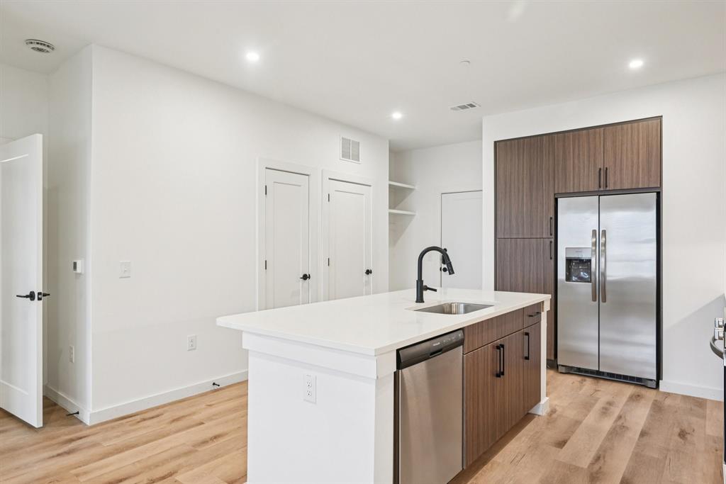 2016 South Ervay Street, Unit A1 Dallas, TX 75215 - Photo 9 of 35 Kitchen with appliances with stainless steel finishes, light wood-style floors, a center island with sink, light stone counters, and recessed lighting