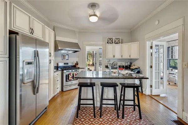 a kitchen with stainless steel appliances granite countertop a dining table chairs refrigerator and cabinets