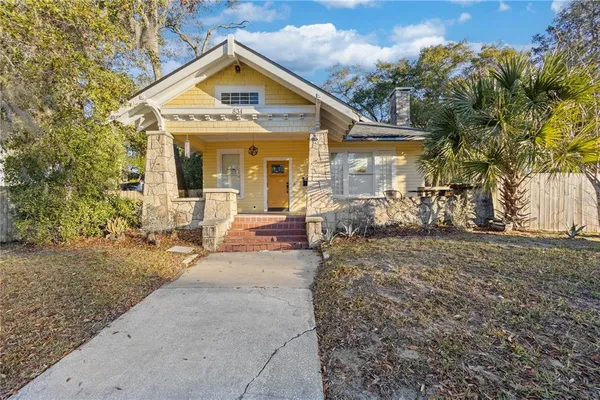 a view of a house with a small yard and large tree