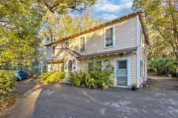 a view of a white house with large windows and a small yard