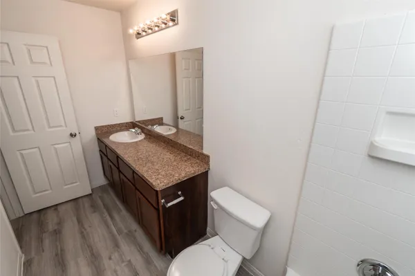 a bathroom with a granite countertop sink toilet and mirror