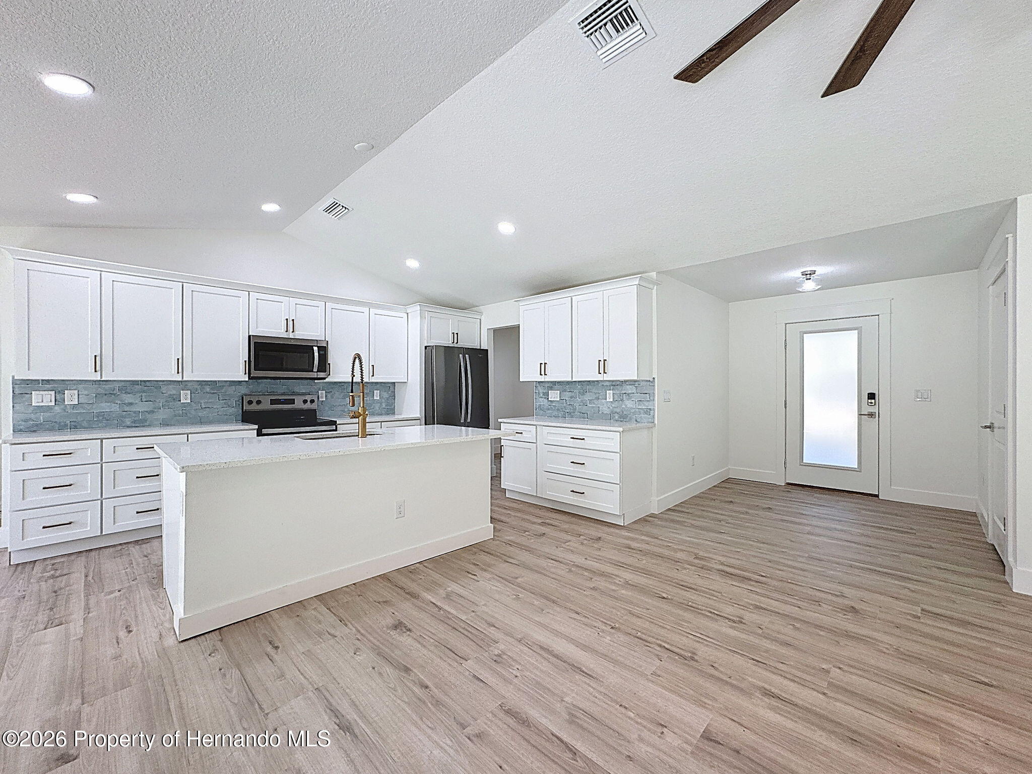 8988 Waterbird Way Weeki Wachee, FL 34613 - Photo 12 of 42 a large white kitchen with stainless steel appliances granite countertop a stove a sink dishwasher and a oven with white cabinets