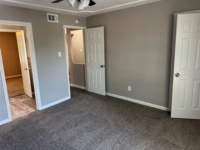 an empty room with closet and a ceiling fan