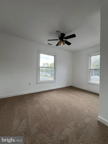 an empty room with windows and ceiling fan