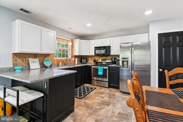 a kitchen with stainless steel appliances granite countertop a refrigerator a sink a stove and island