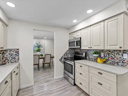 a kitchen with stainless steel appliances white cabinets and wooden floor