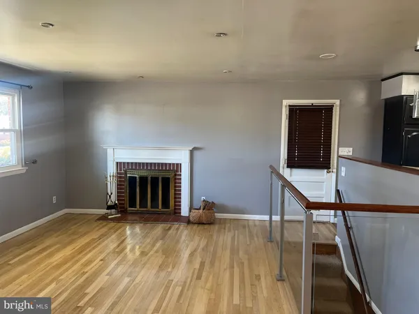 a view of a livingroom with wooden floor and a fireplace