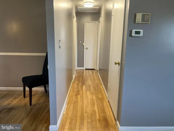 a view of a hallway with wooden floor and a bathroom