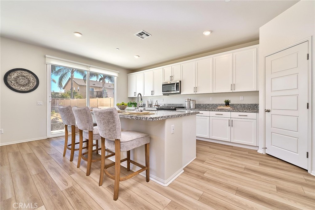32846 Forgecroft Street Menifee, CA 92584 - Photo 14 of 48 a kitchen with a table chairs a oven a counter space and a window