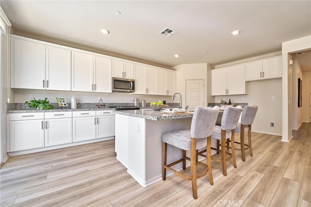 32846 Forgecroft Street Menifee, CA 92584 - Photo 15 of 48 a kitchen with a white cabinets and chairs in it