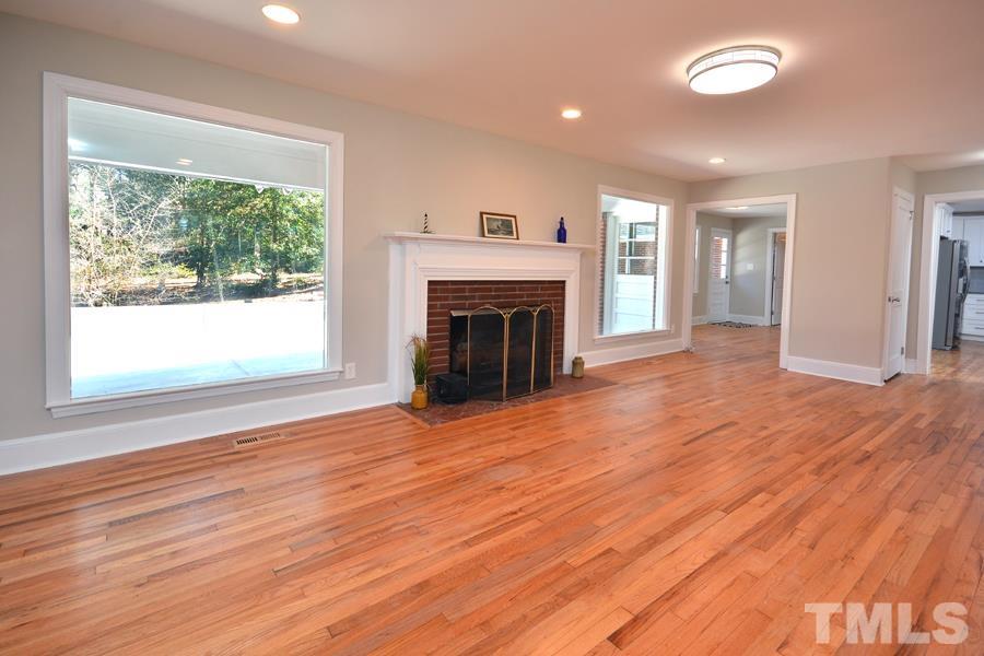 402 Monticello Avenue Durham, NC 27707 - Photo 15 of 24 an empty room with wooden floor fireplace cabinet and windows