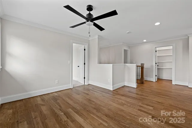 a view of empty room with wooden floor and ceiling fan