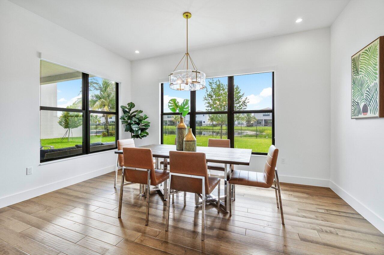 17128 Watersprite Lakes Road Boca Raton, FL 33496 - Photo 18 of 56 a dining room with wooden floor a chandelier a glass table and chairs