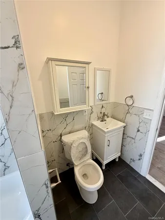 a bathroom with a granite countertop toilet a sink and a mirror