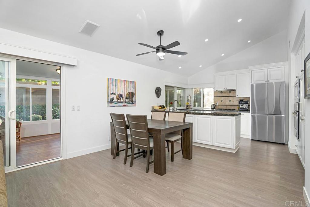 1237 Granada Way San Marcos, CA 92078 - Photo 6 of 27 a kitchen with stainless steel appliances kitchen island granite countertop a refrigerator a stove a dining table and chairs with wooden floor