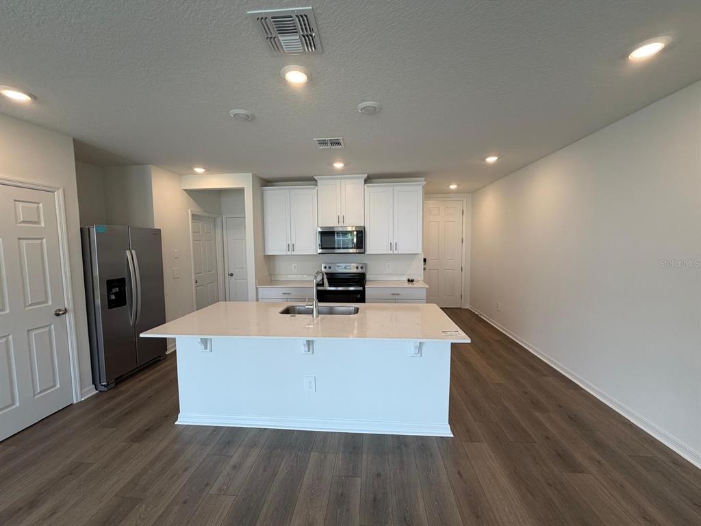 4244 Ranch House Road St. Cloud, FL 34772 - Photo 3 of 34 a large kitchen with stainless steel appliances a large counter top and wooden floors