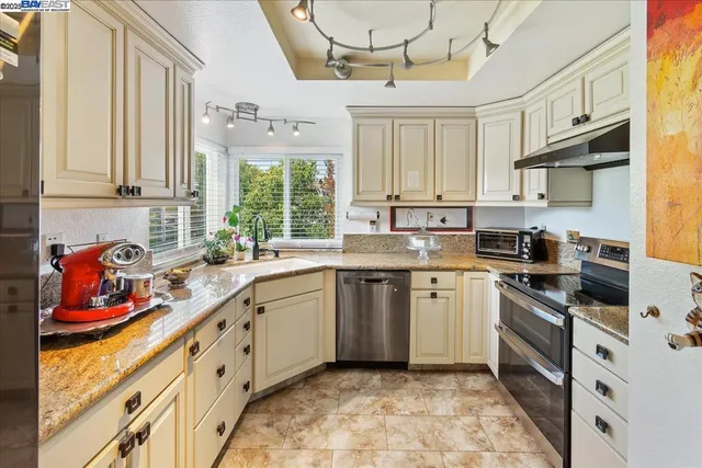 a kitchen with stainless steel appliances granite countertop white cabinets sink and window