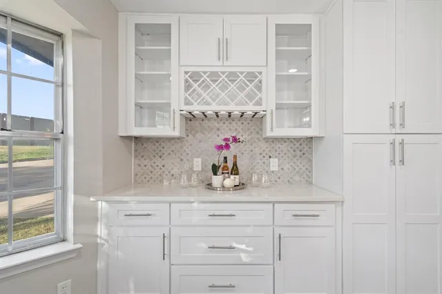 a kitchen with white cabinets and window