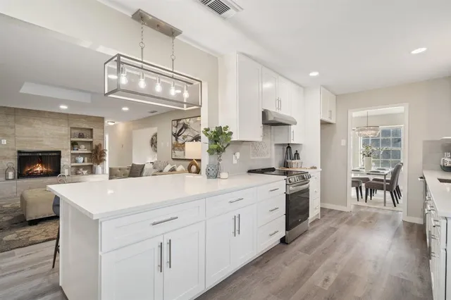 a kitchen with a sink dishwasher a stove a dining table and chairs with wooden floor