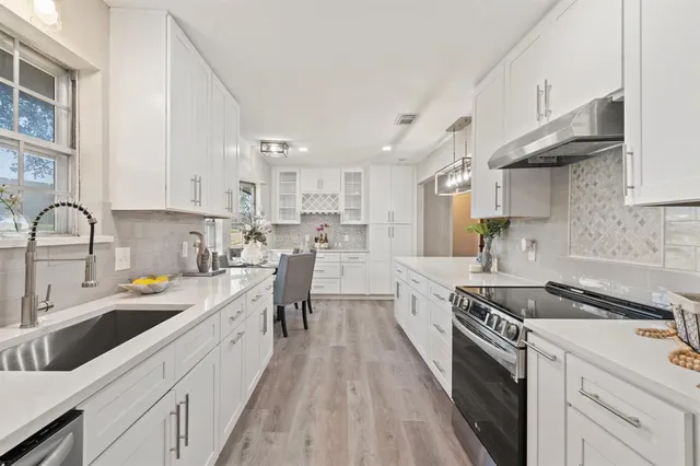 a kitchen with granite countertop a sink a counter space stainless steel appliances and cabinets