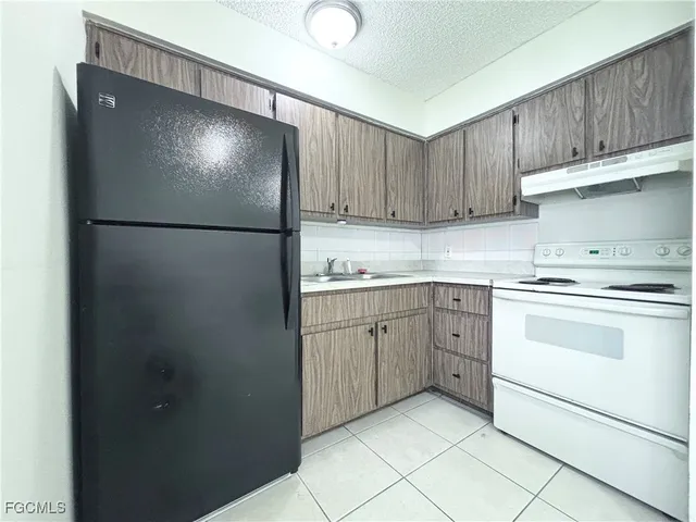a kitchen with a refrigerator sink and cabinets