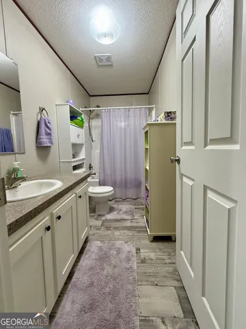 a bathroom with a granite countertop sink a toilet and shower