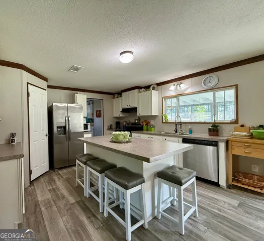 a kitchen with kitchen island a counter top space a sink stainless steel appliances and cabinets