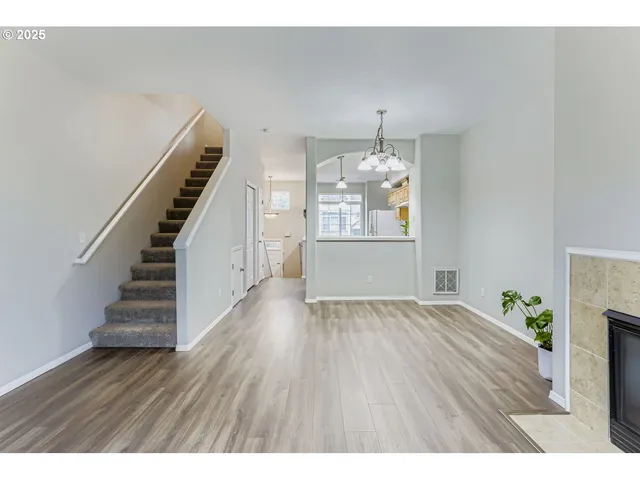 a view of an empty room with wooden floor and stairs