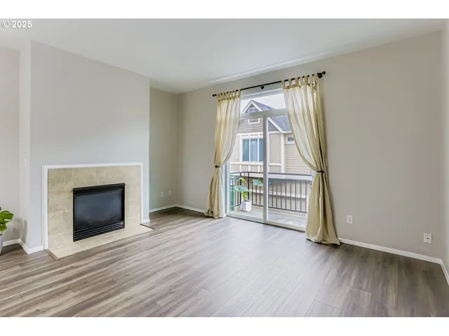 a view of empty room with wooden floor and fireplace