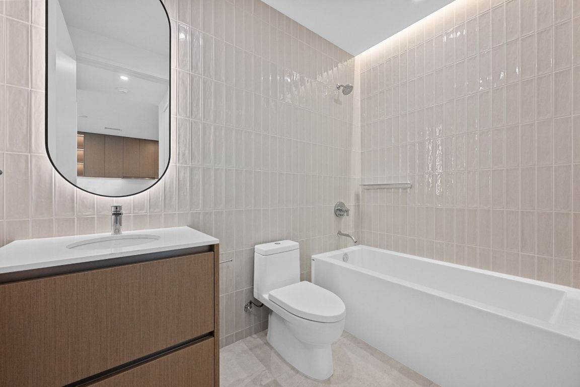 610 Davis Street, Unit 2103 Austin, TX 78701 - Photo 20 of 32 a bathroom with a toilet a sink a mirror and bathtub