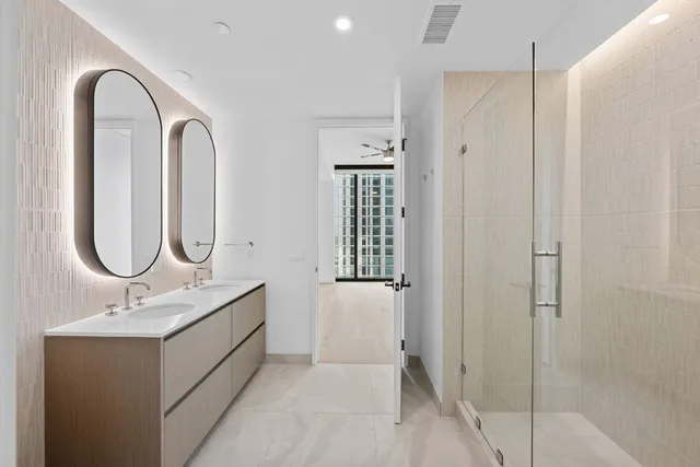 a bathroom with a double vanity sink a mirror and a shower