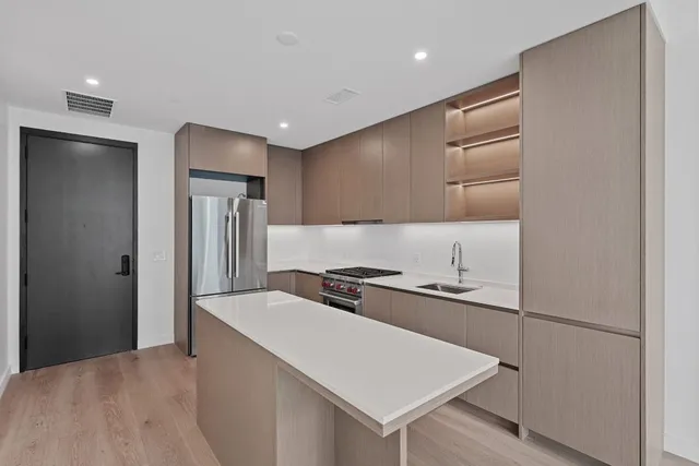 a kitchen that has a sink a refrigerator and a stove top oven
