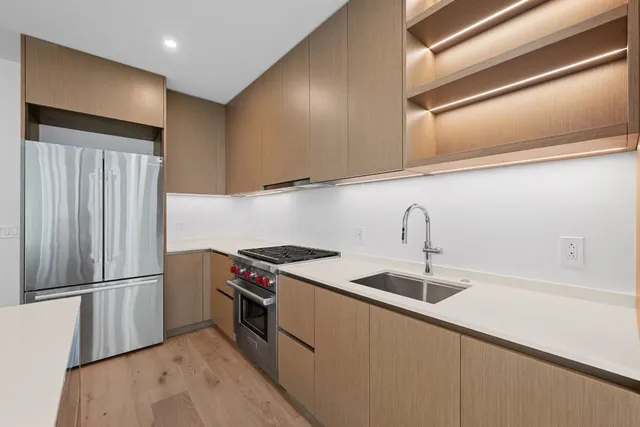 a kitchen with stainless steel appliances granite countertop a sink a stove and a refrigerator