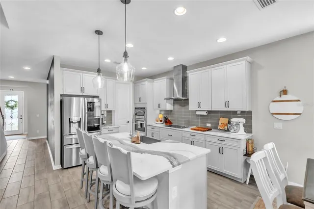 a kitchen with stainless steel appliances kitchen island granite countertop a table chairs and a refrigerator