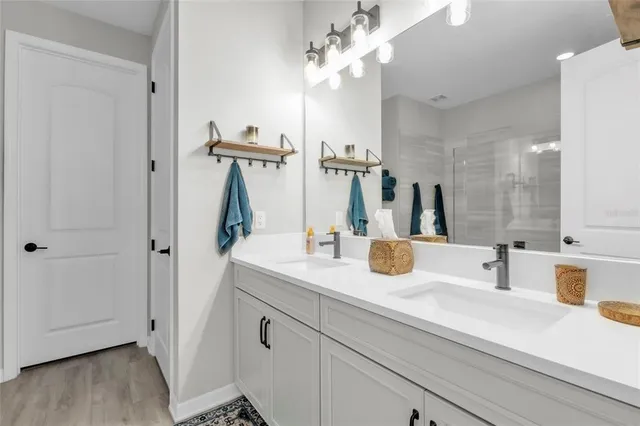 a bathroom with a double vanity sink a toilet and shower