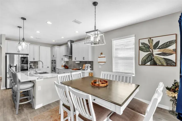a kitchen with a dining table chairs refrigerator and microwave