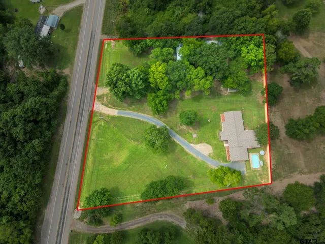 an aerial view of residential houses with outdoor space and trees