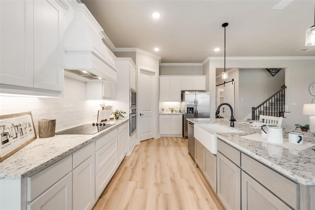 250 Brown Road Leonard, TX 75452 - Photo 14 of 29 Gourmet kitchen featuring a large center island, white cabinetry, integrated appliances, wood-finish flooring, and a subway tile backsplash